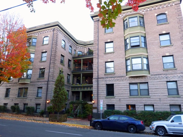 Historic brick apartment buildings with bay windows and autumn foliage in an urban courtyard setting. — Northwest District, Portland