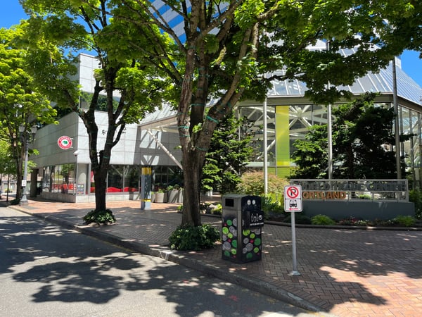 Urban plaza with mature trees, modern storefronts, and a recycling bin in downtown Portland, Oregon. — Downtown, Portland
