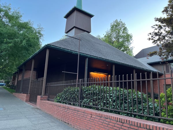 Zion Lutheran Church, a modern chapel with distinctive peaked roof and brick base, viewed from the street entrance. — Goose Hollow, Portland