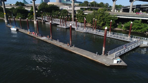 Waterfront park with pedestrian docks and walkways along an urban river, with city bridges and buildings visible in the… — Old Town, Portland