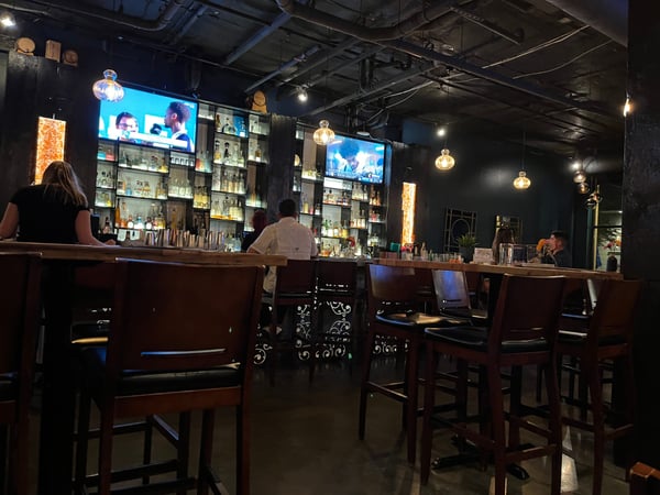 Modern cocktail bar interior with illuminated bottle display, pendant lighting, and bar seating in Portland. — Pearl District, Portland