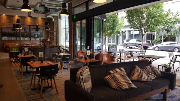 Modern hotel lobby and café with brick walls, pendant lighting, and street-facing seating at Canopy by Hilton Portland… — Pearl District, Portland