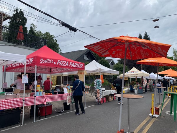 Outdoor food market with vendor tents and umbrellas in a residential street, featuring pizza and other food vendors. — Portland