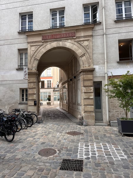 Arched stone passageway with classical architecture leading to a courtyard in Paris, with bicycles parked at the… — 11th Arrondissement, Paris