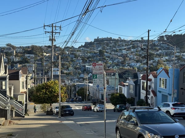 Residential street in San Francisco with Victorian and Edwardian houses cascading up a hillside, viewed from street…